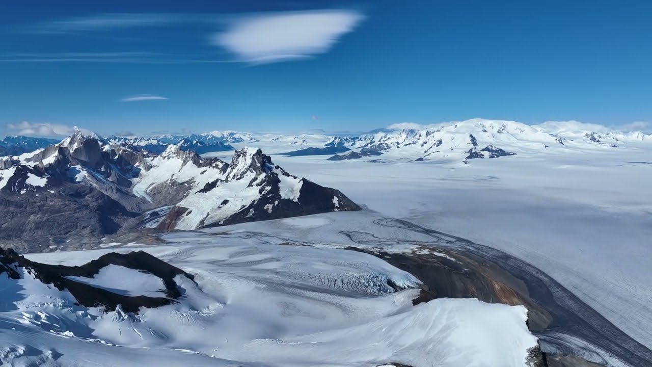 A lone explorer trekking across a massive, blue-tinted glacier in Patagonia
